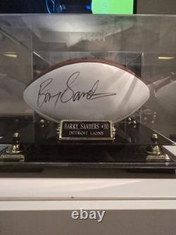 Ballon de football NFL officiel autographed par Barry Sanders avec vitrine en verre et certificat d'authenticité.